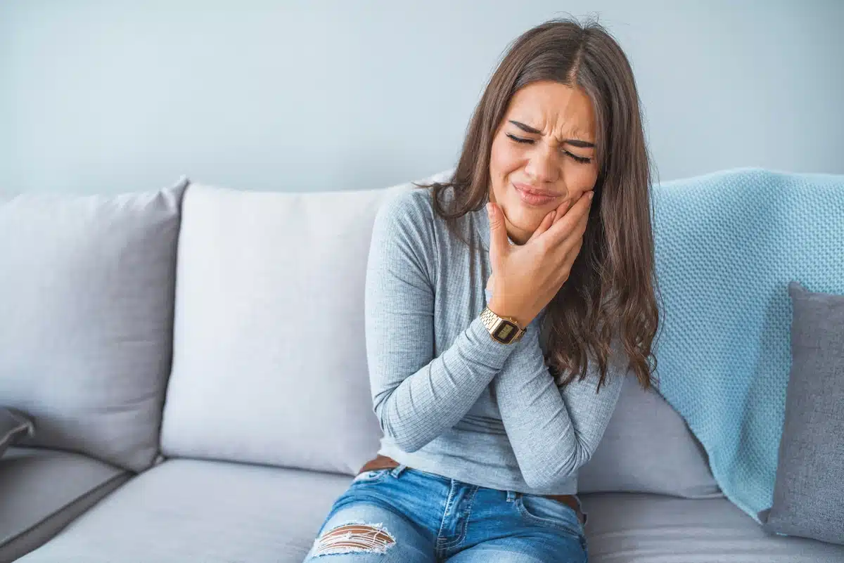 woman sitting at the couch with tooth ache
