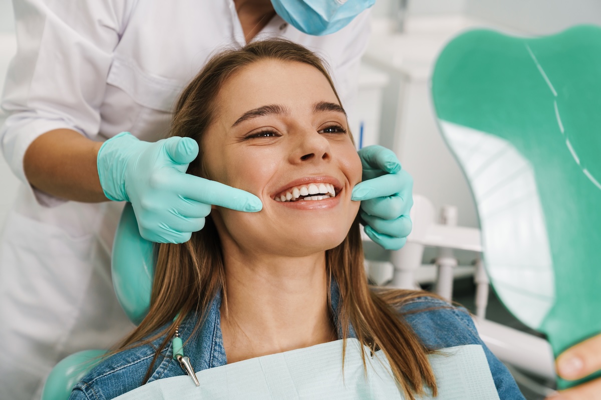 young woman smiling while looking at mirror in dental clinic