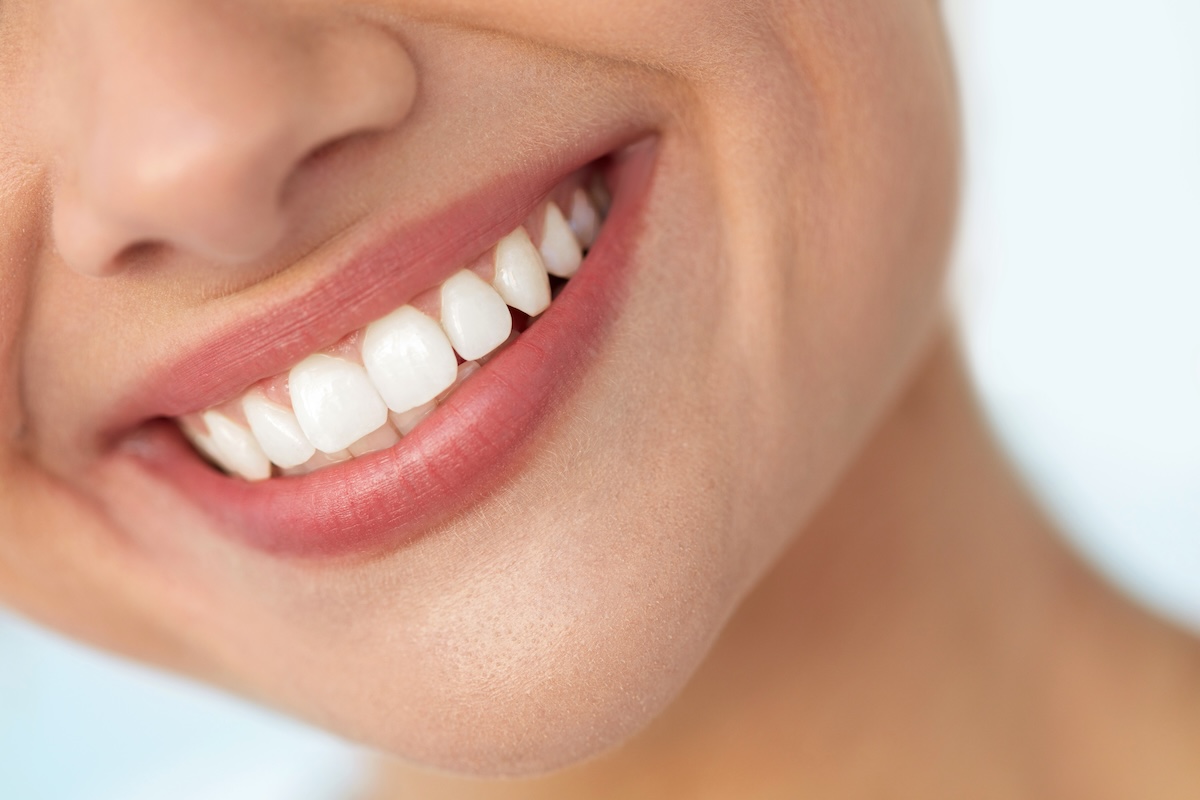 Close-up of a person smiling, showing clean, white teeth and smooth, pink lips
